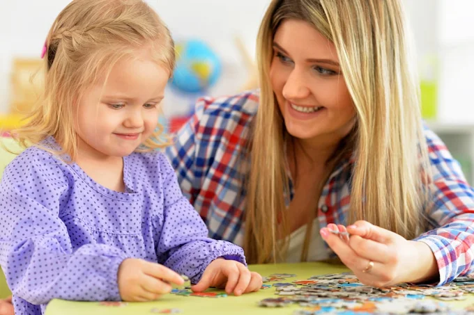 A support worker and a young child piecing together a puzzle together, building focus and connection through play