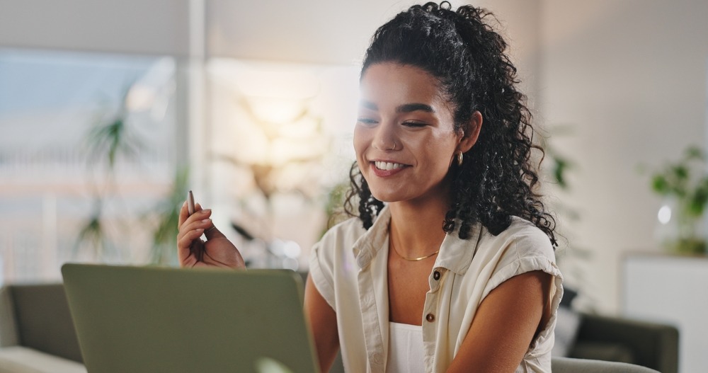 A relaxed HR professional smiles at her laptop, reflecting the calm confidence a supportive workplace culture can bring