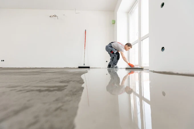 Concrete contractor applying self-levelling compound to prepare a floor for a commercial-grade flooring finish